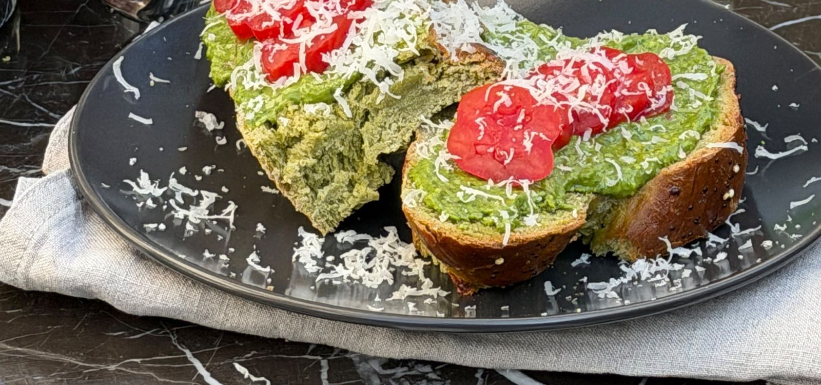 Matcha Pesto auf einem Brot mit Tomaten und Parmesan garniert