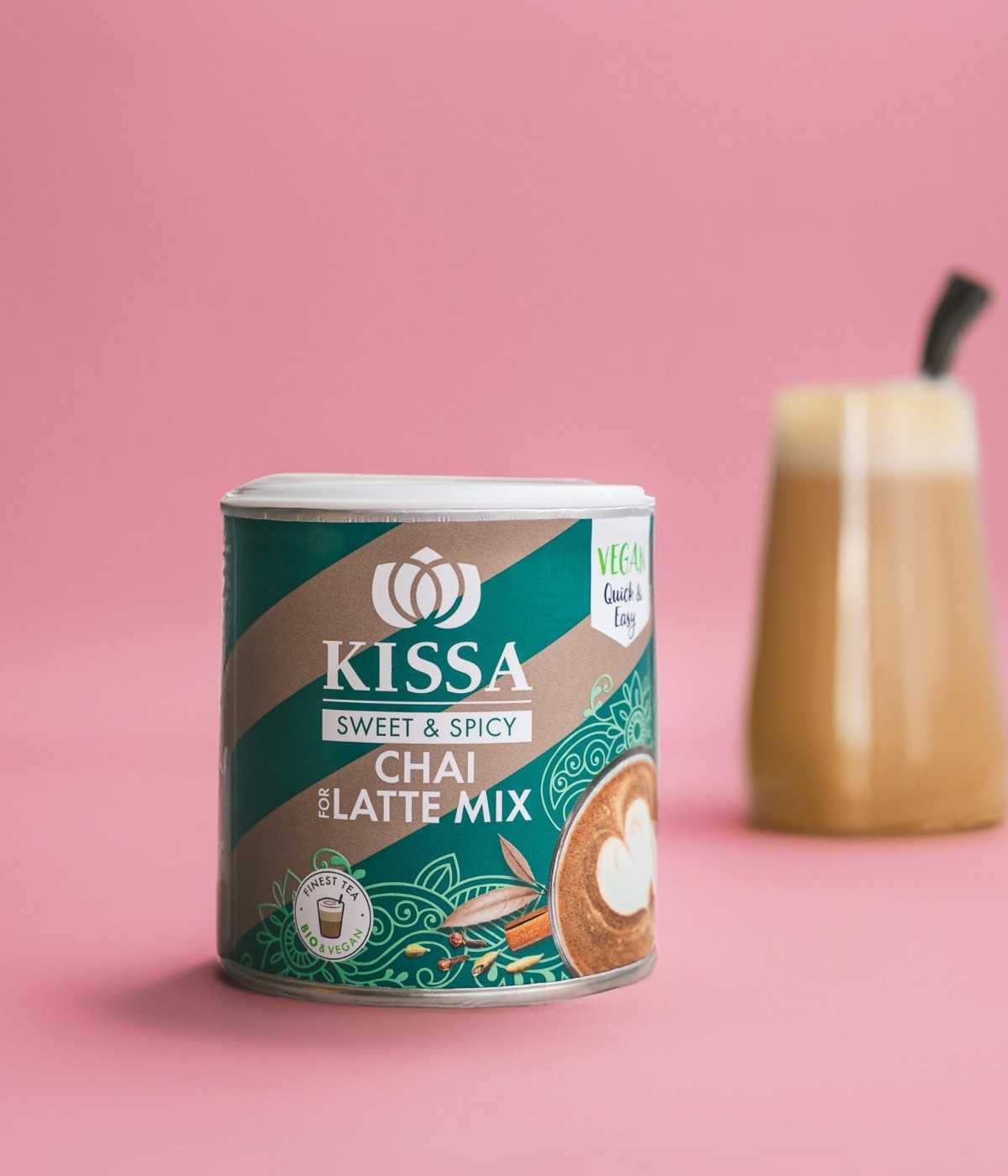 Bio Chai for Latte Mix in moderner Verpackung neben chai latte vor einem stilvollen rosa Hitergrund
