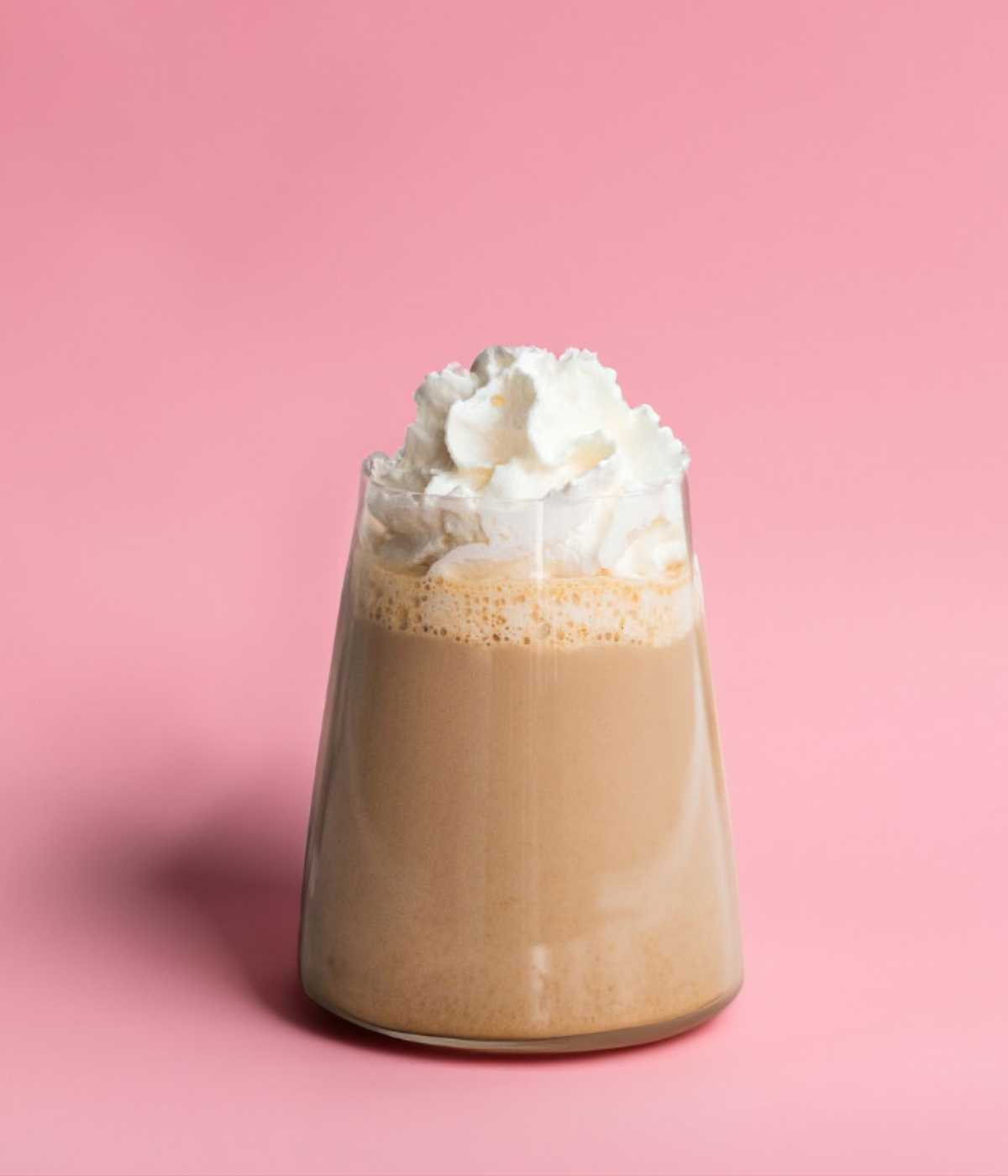 Chai Latte mit cremigem Milchschaum auf Rosahintergrund.