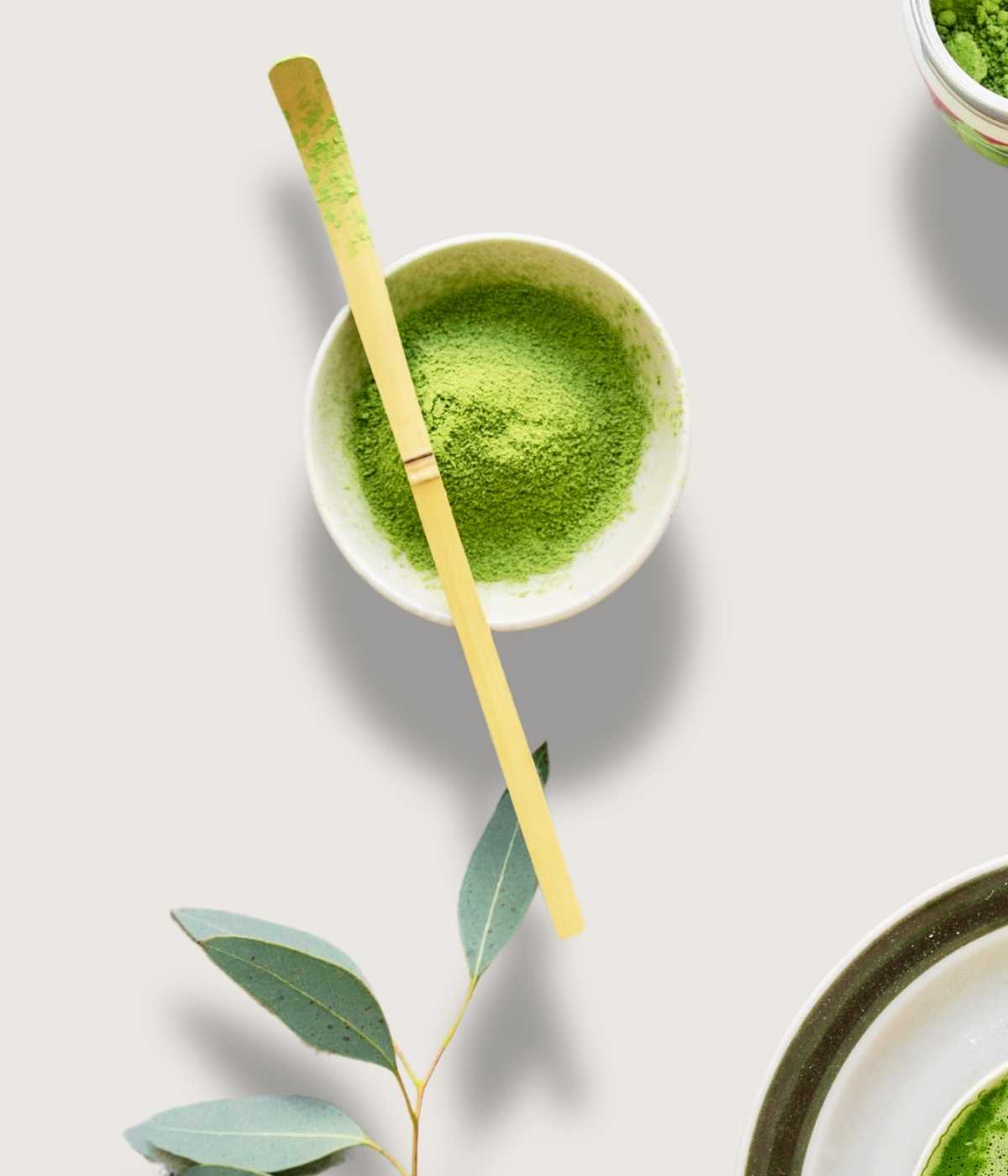 Matcha-Bambuslöffel liegt auf einer Schale mit Matcha-Pulver.