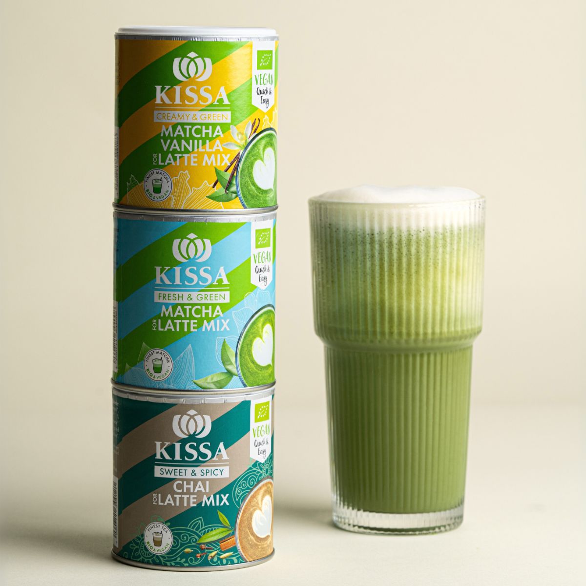 KISSA Latte Mix Bundle mit drei Sorten – Chai, Vanilla und Matcha neben cremigem Matcha Latte auf hellem Hintergrund