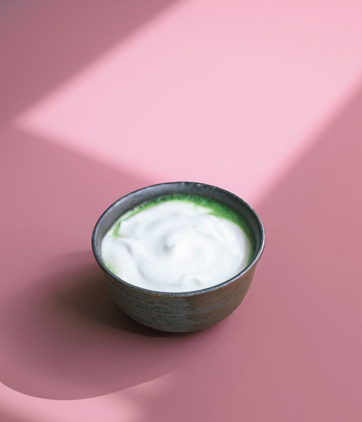 Matcha Schale mit cremigem, schaumigem Matcha Latte auf hellem Untergrund.