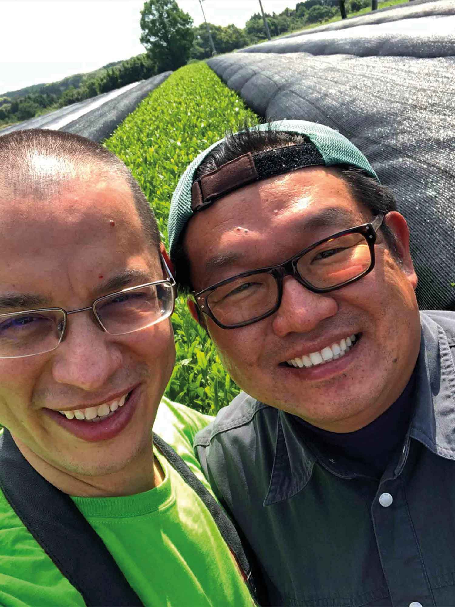 Two men smiling with a tencha farm background