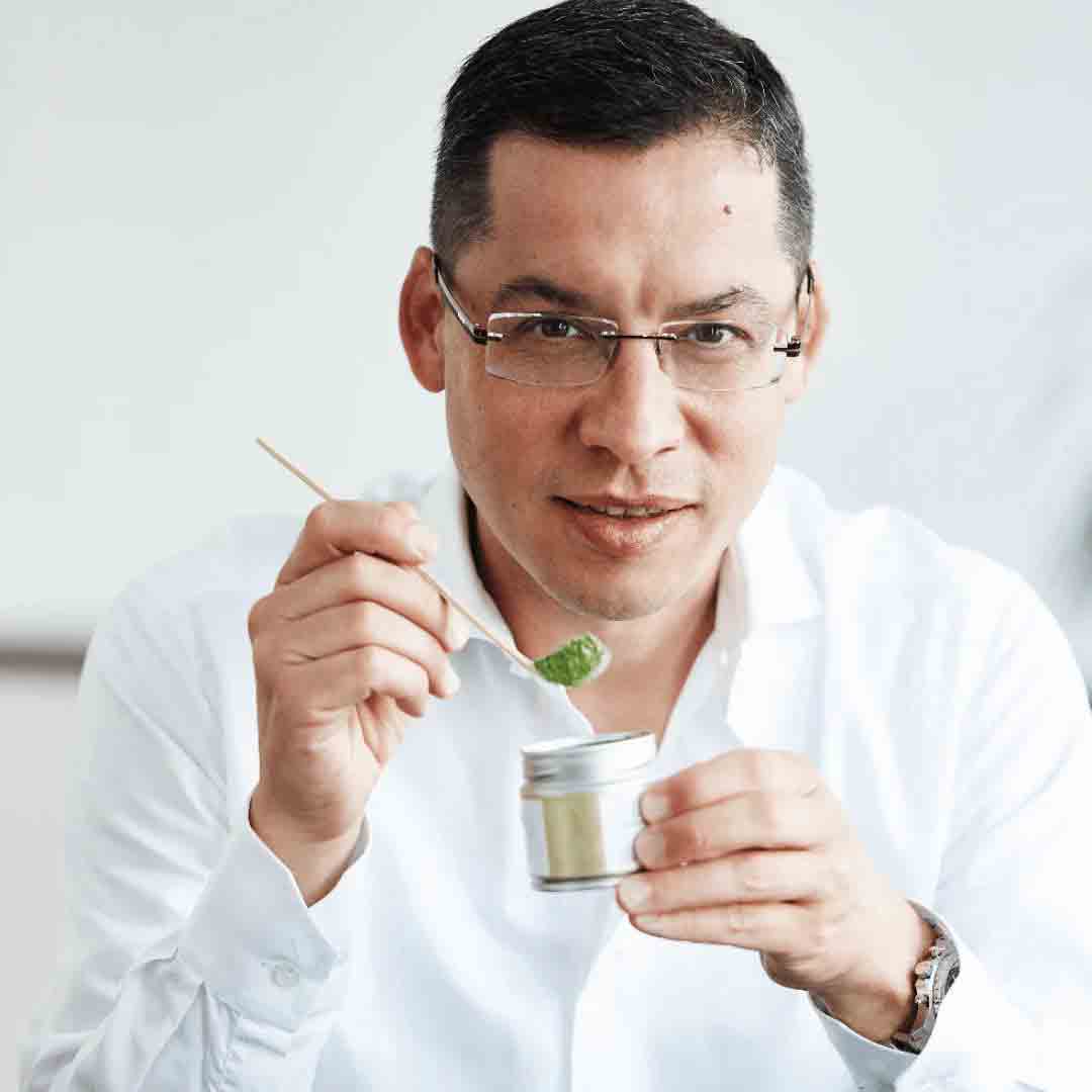 a man holding a wooden stick with matcha