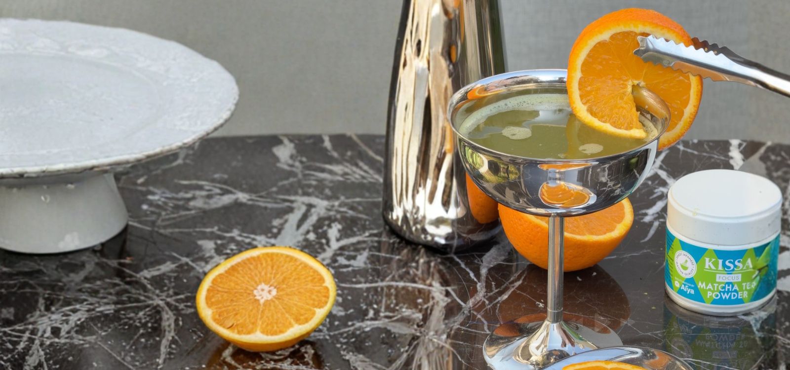 Matcha Mimosa, garniert mit einer Orangenscheibe, neben einer Dose KISSA Matcha Fokus
