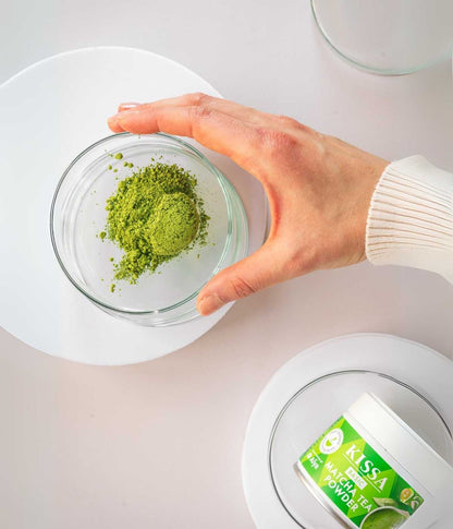 Matcha Gruenteepulver in Schüssel mit Hand