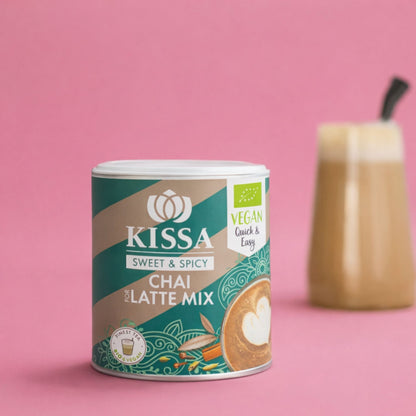 Bio Chai for Latte Mix in moderner Verpackung neben chai latte vor einem stilvollen rosa Hitergrund