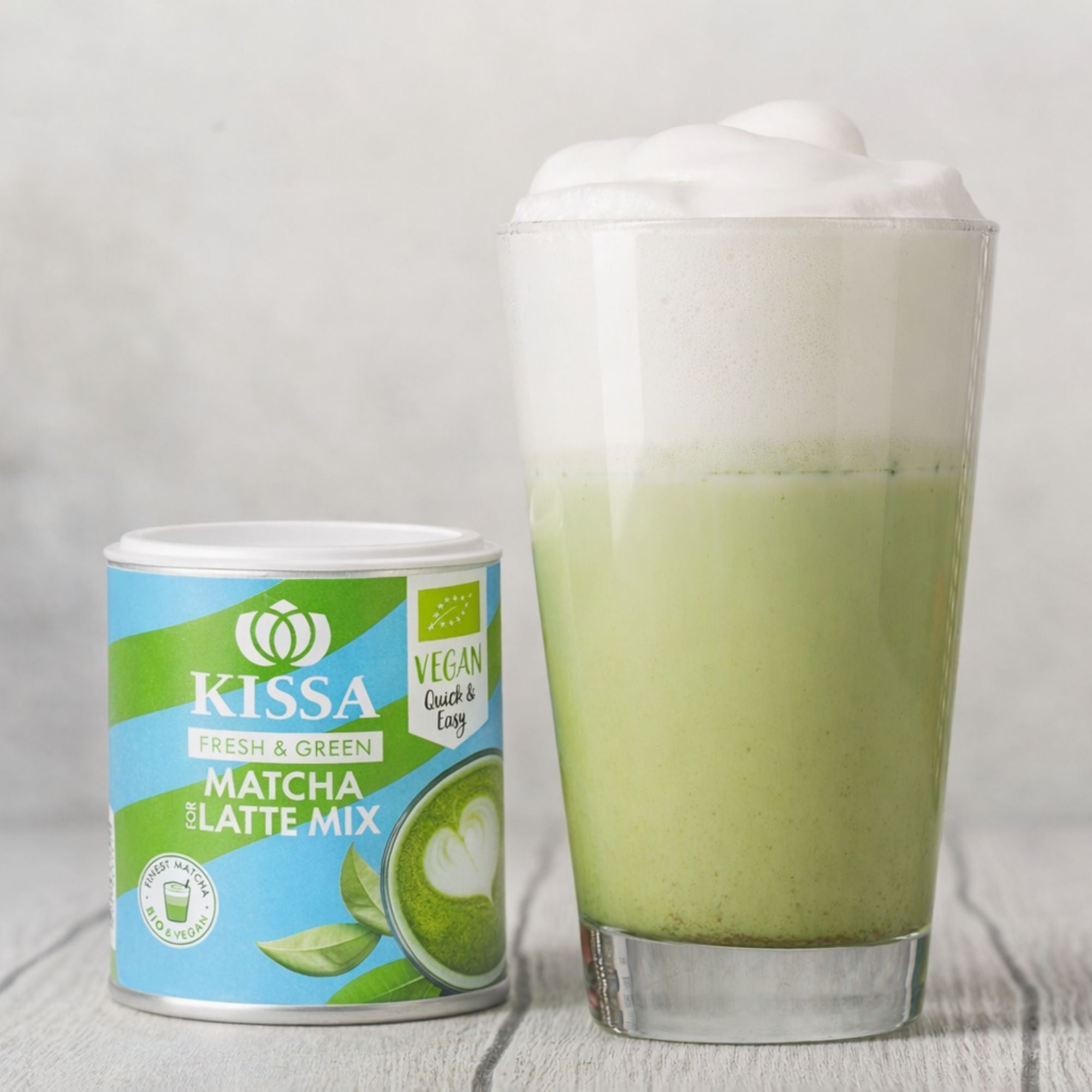 KISSA Matcha Latte Mix – cremiger Bio-Latte in ansprechender Verpackung neben cremigem Matcha Latte auf hellem Hintergrund