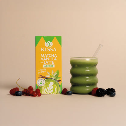 Matcha Stick Box neben einem Matcha Latte, davor liegen Waldbeeren